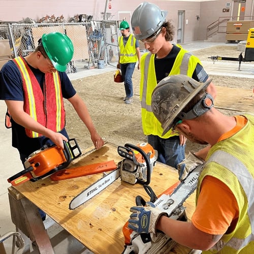 Group of construction workers investigating their chainsaws.