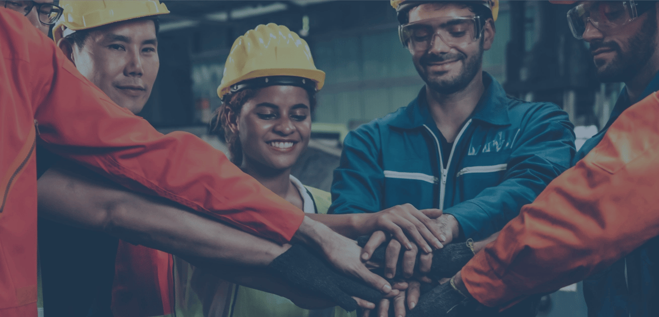 A group of construction coworkers in a circle putting their hands in the middle.