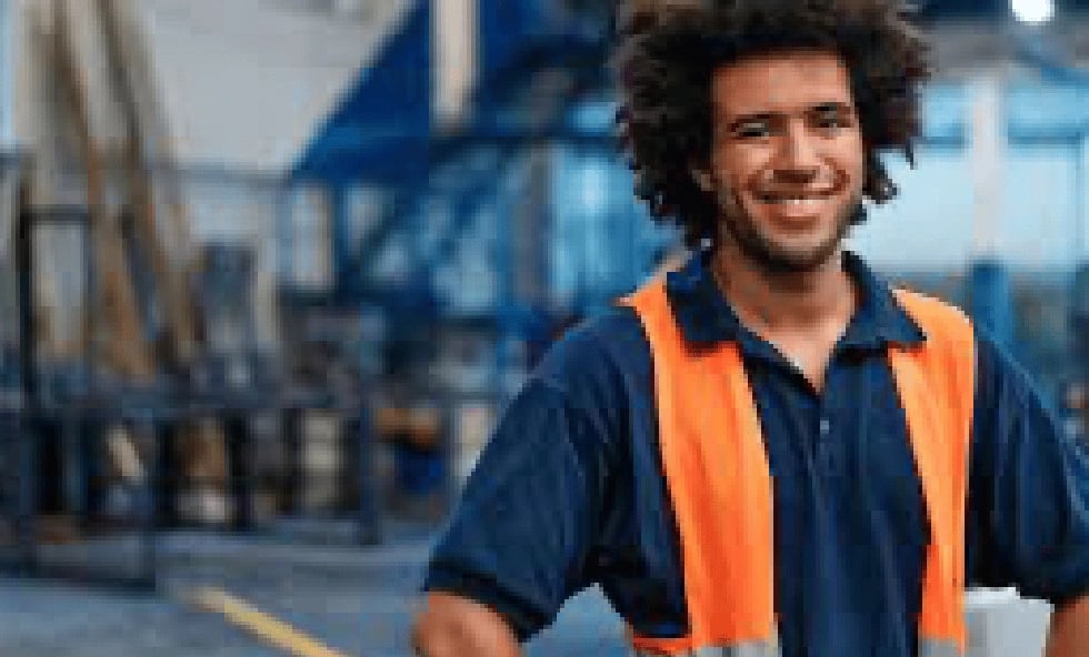 Man wearing a safety vest smiling in a construction company building.