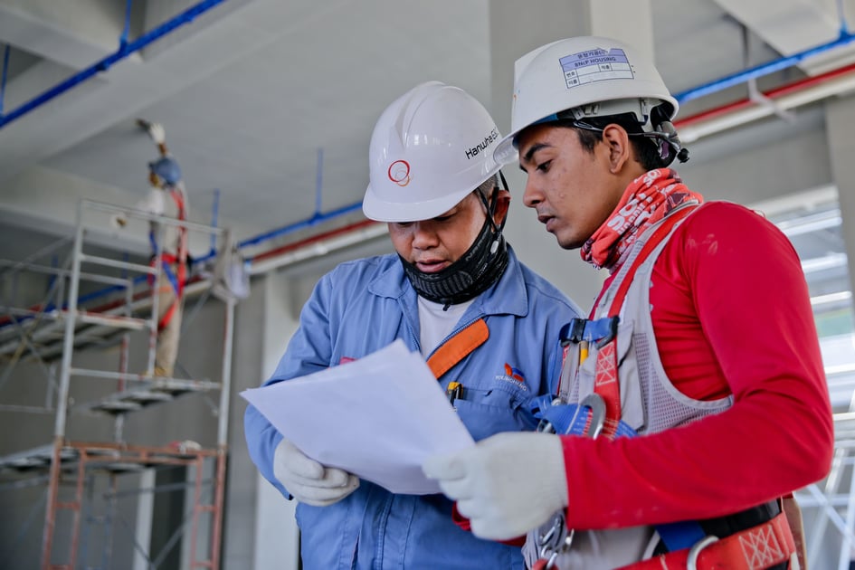 Two construction workers reviewing a document.