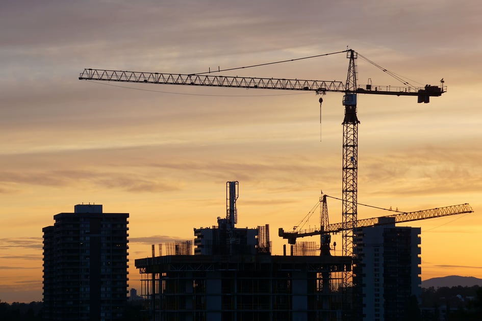 A tower crane in a city in the sunrise.